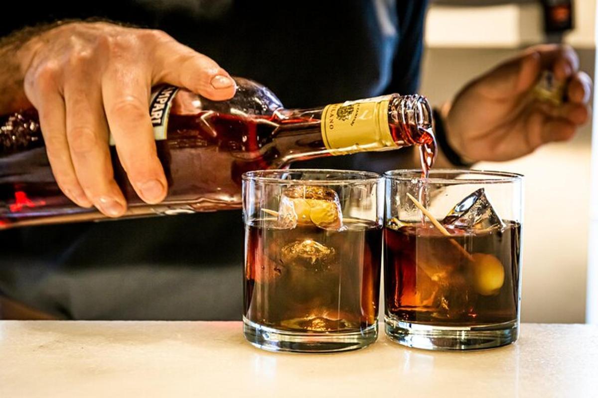 a person pouring a bottle of wine into two glasses