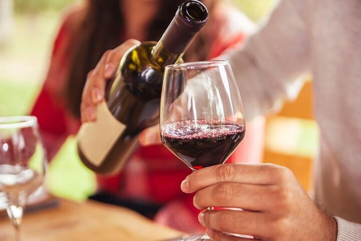 una persona sirviendo una copa de vino tinto