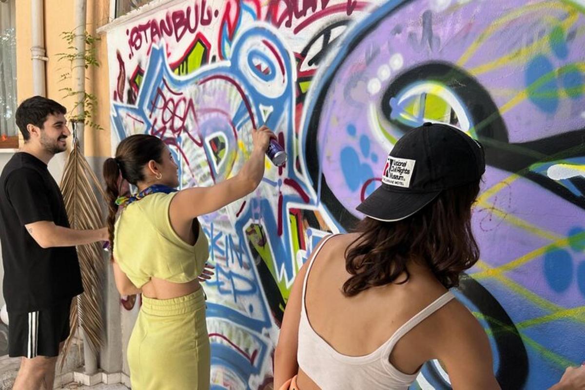 a couple of people painting a wall with graffiti