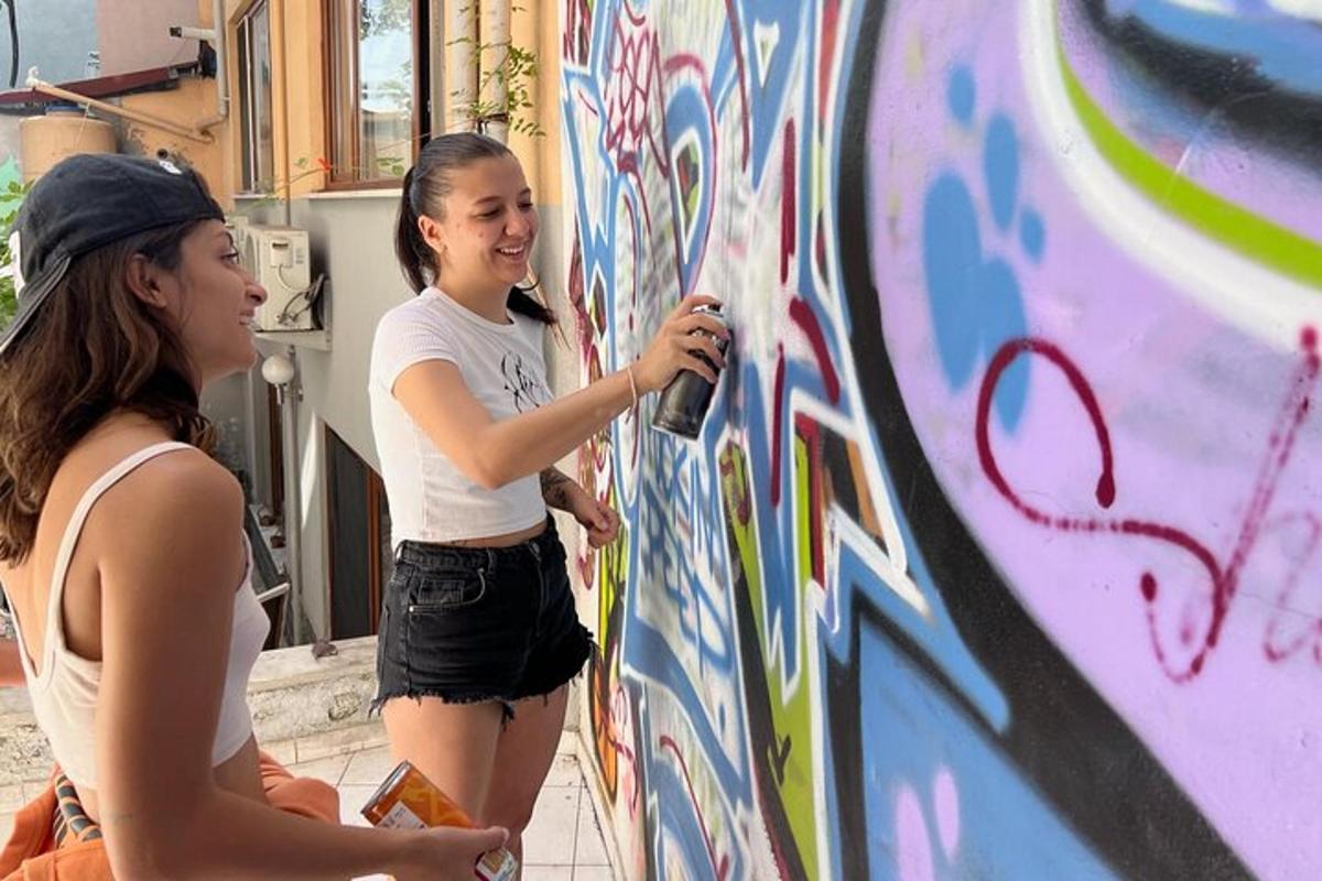 zwei Mädchen bemalen eine Wand mit Graffiti
