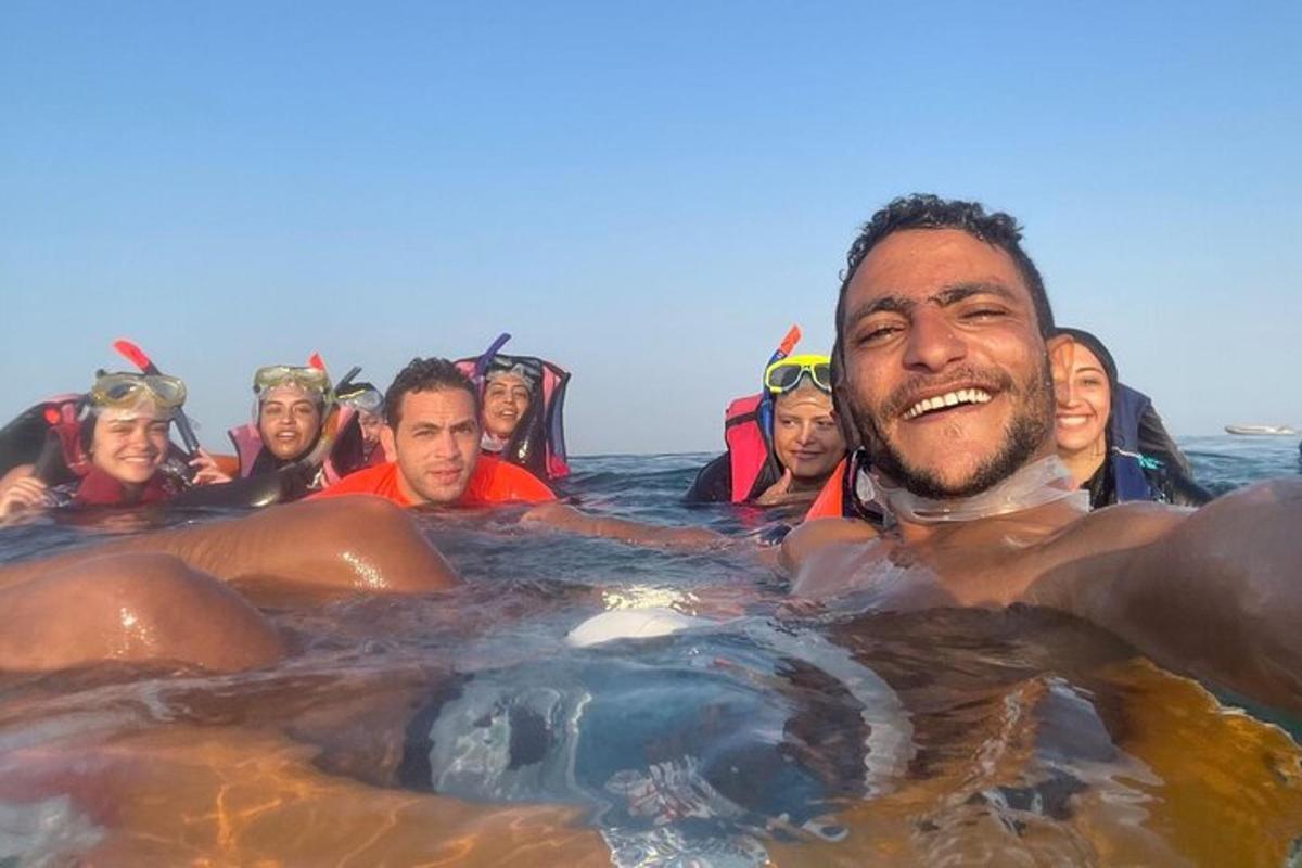žmonių grupė vandenyje su hipopotamu