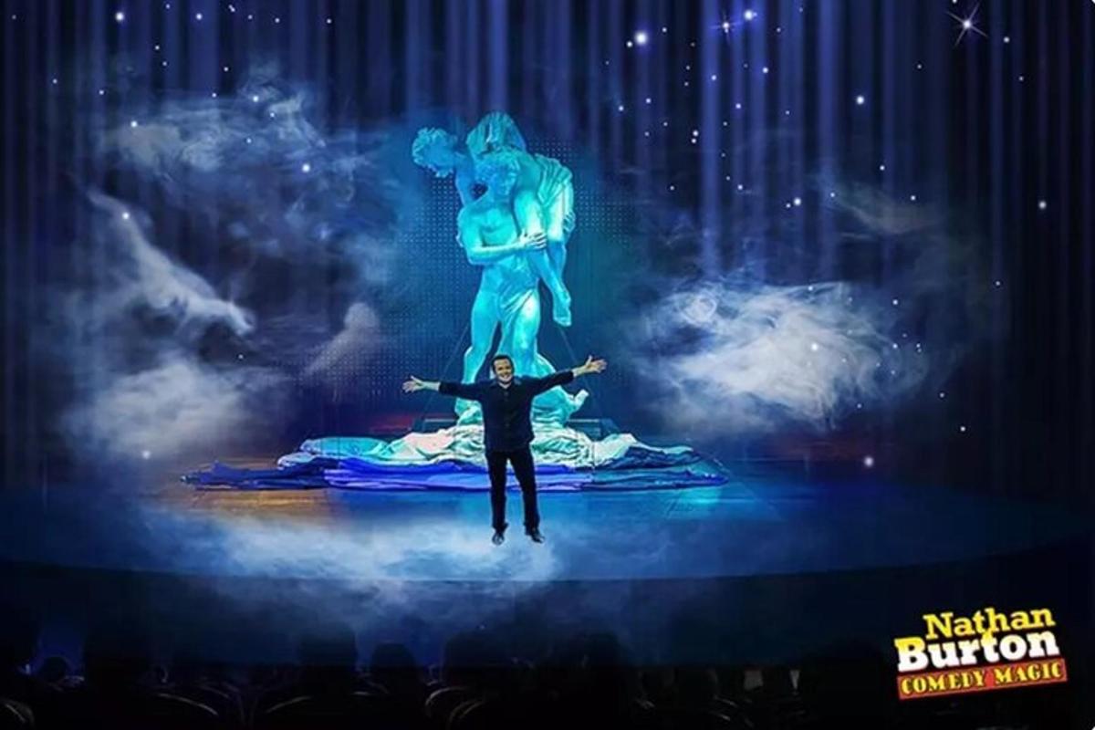 a man standing on a stage in front of a statue