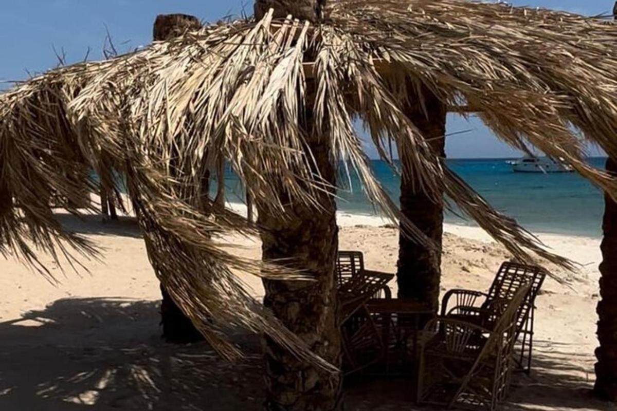 una capanna di paglia su una spiaggia con sedie e l'oceano