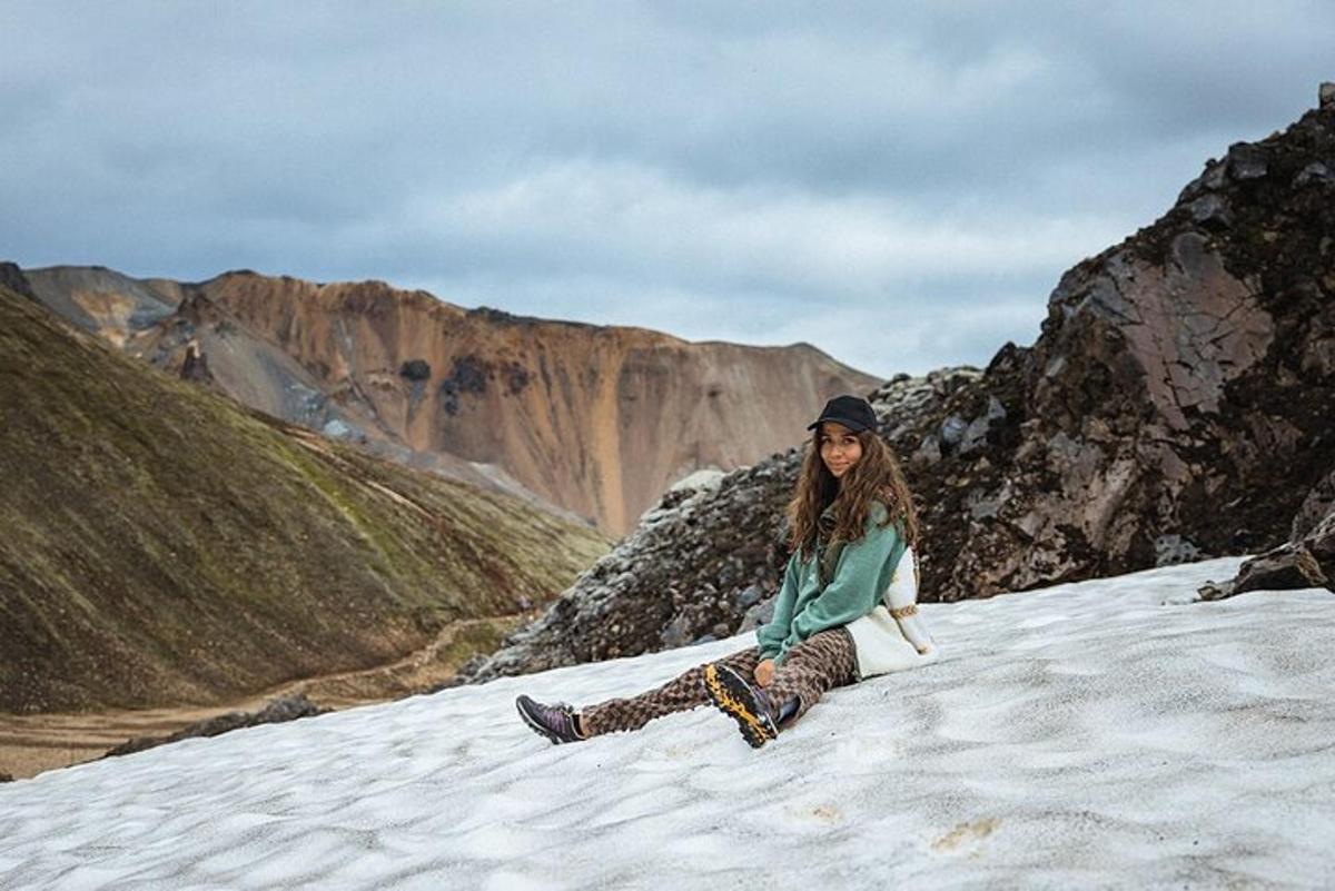 una mujer sentada en la cima de una montaña cubierta de nieve