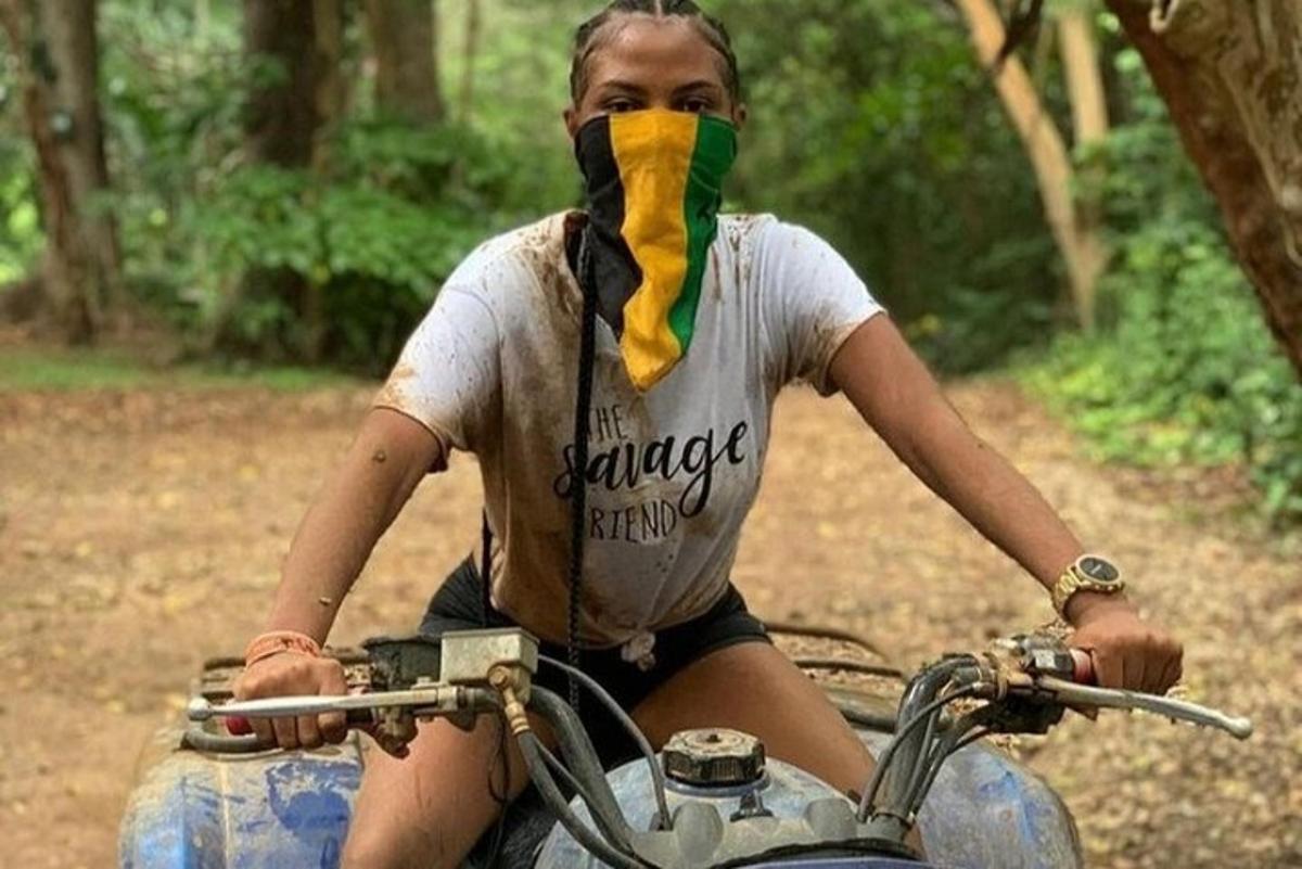 seorang wanita duduk di atas motosikal dengan bandana di mukanya