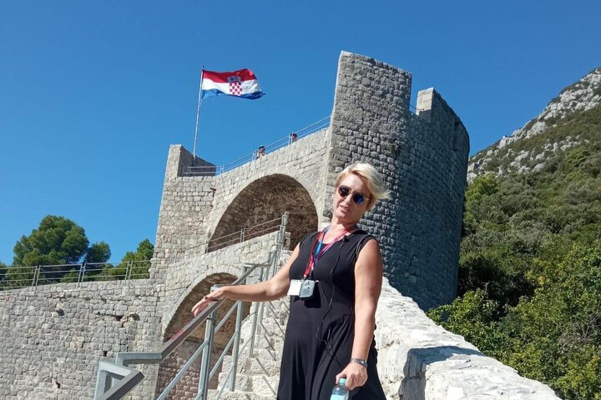 Una mujer parada frente a un castillo con una bandera.