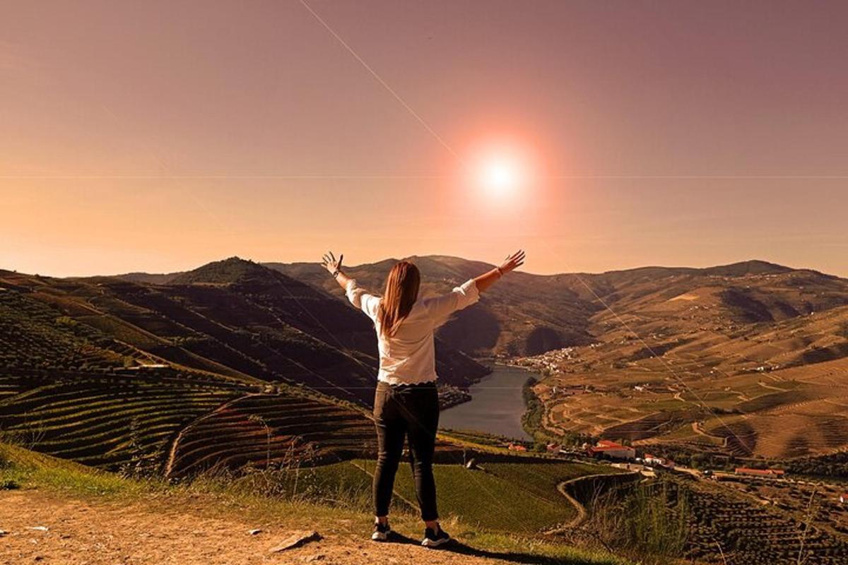 a woman standing on top of a hill flying a kite