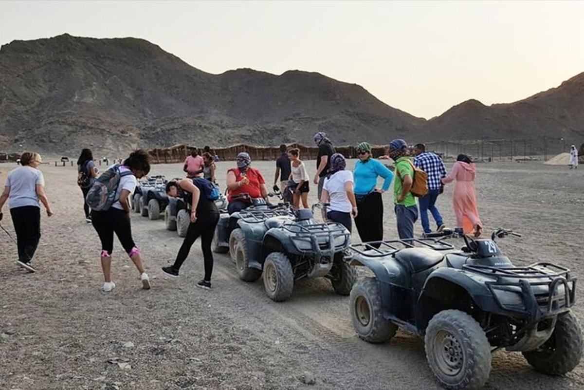 a group of people standing next to atvs and people standing around