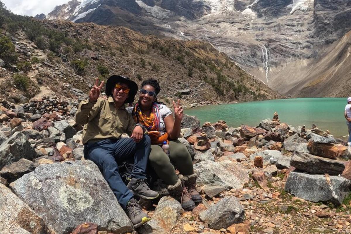 dua orang duduk di atas batu di sebelah tasik