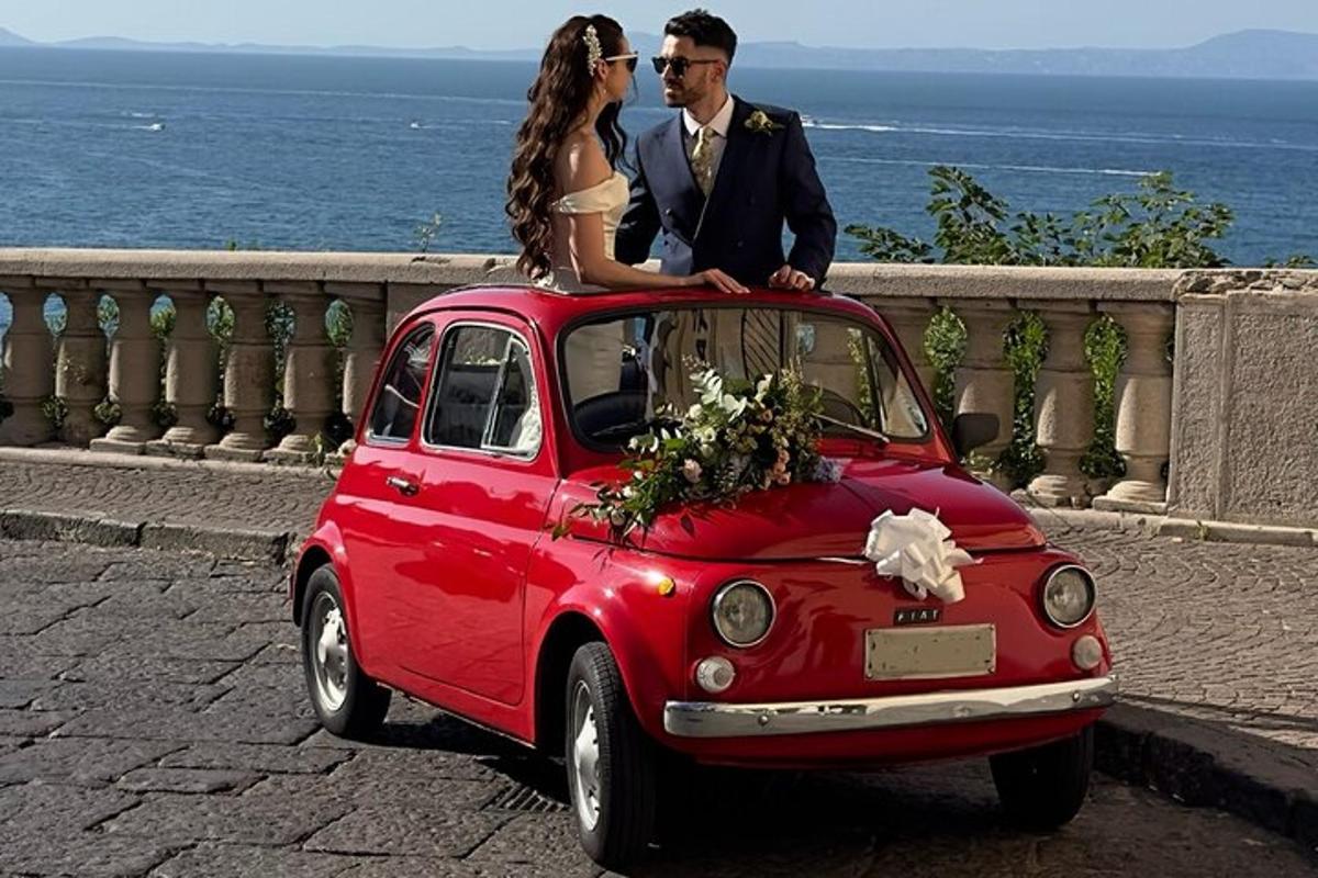 a bride and groom sitting on top of a small car
