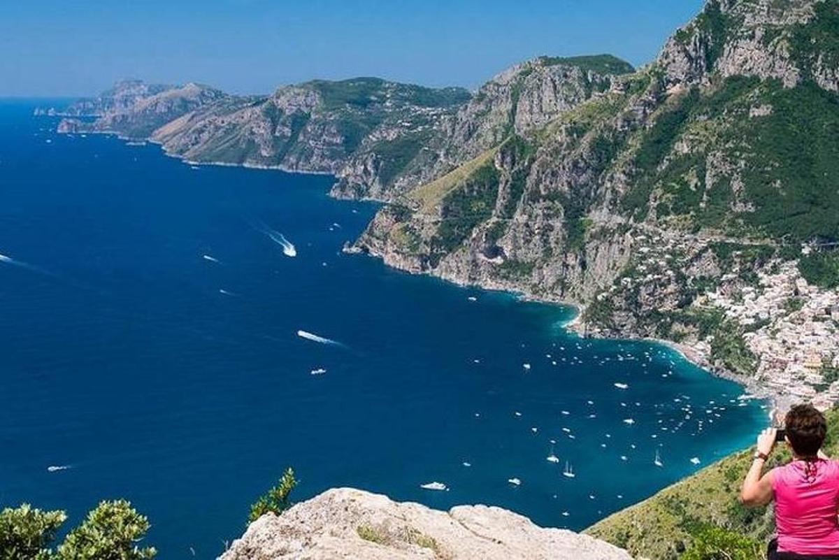 жінка стоїть на скелі та фотографує океан