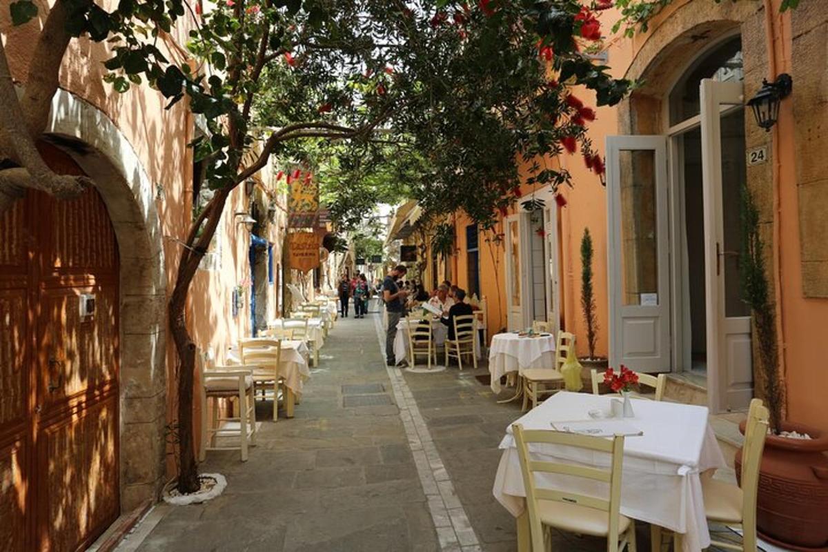 ένας δρόμος με τραπέζια και καρέκλες και ανθρώπους που κάθονται σε τραπέζια