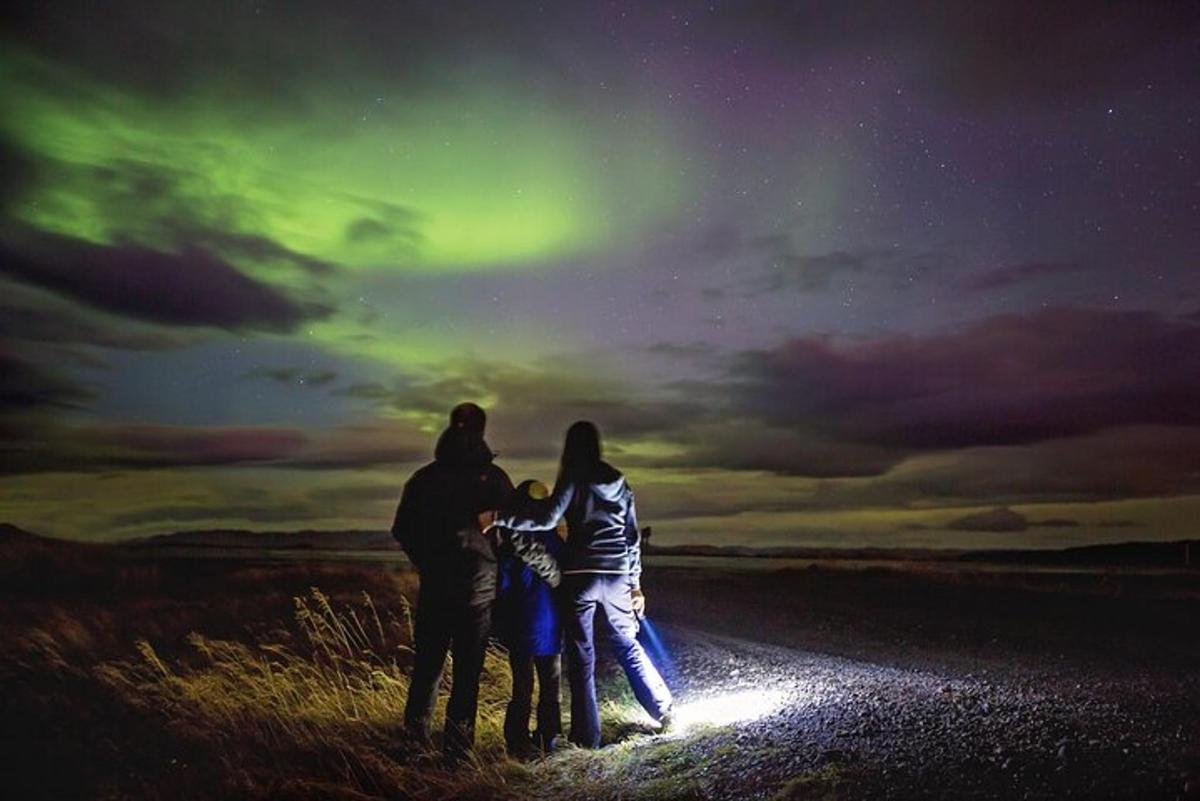 un gruppo di tre persone in piedi sotto l'aurora boreale