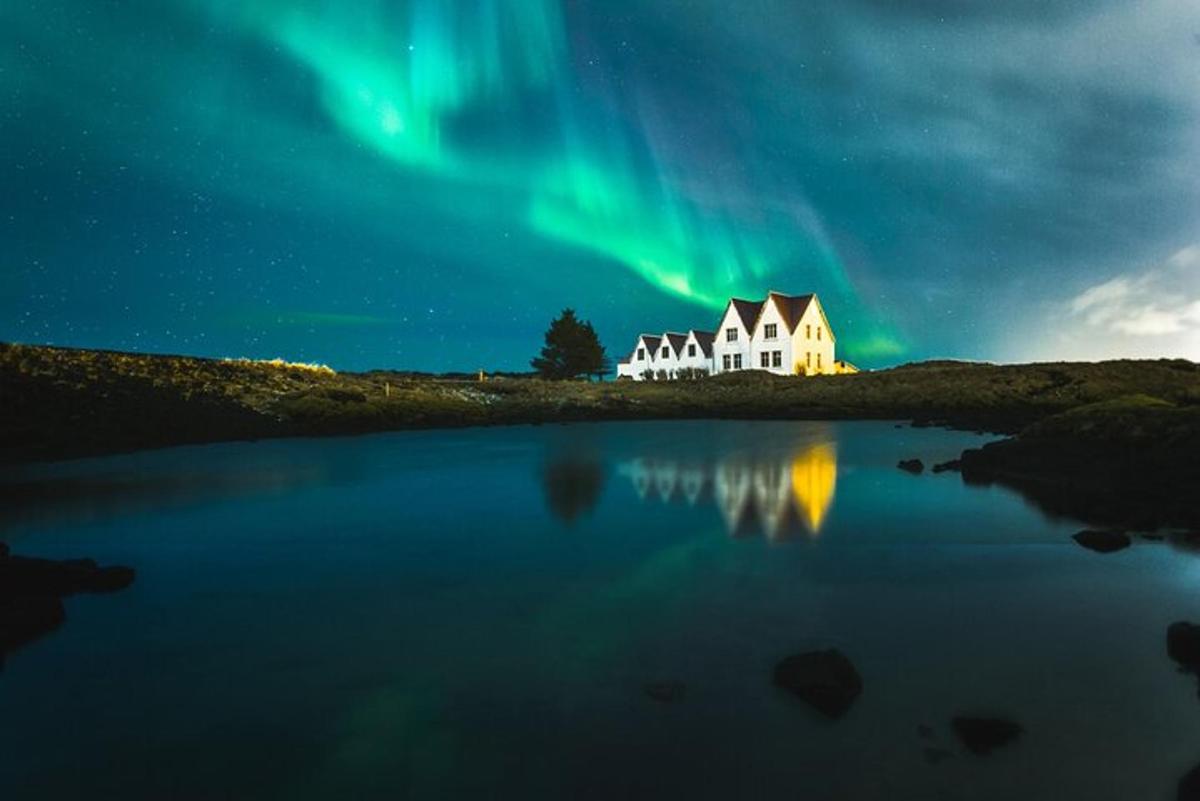 Una imagen de una casa bajo la aurora boreal.
