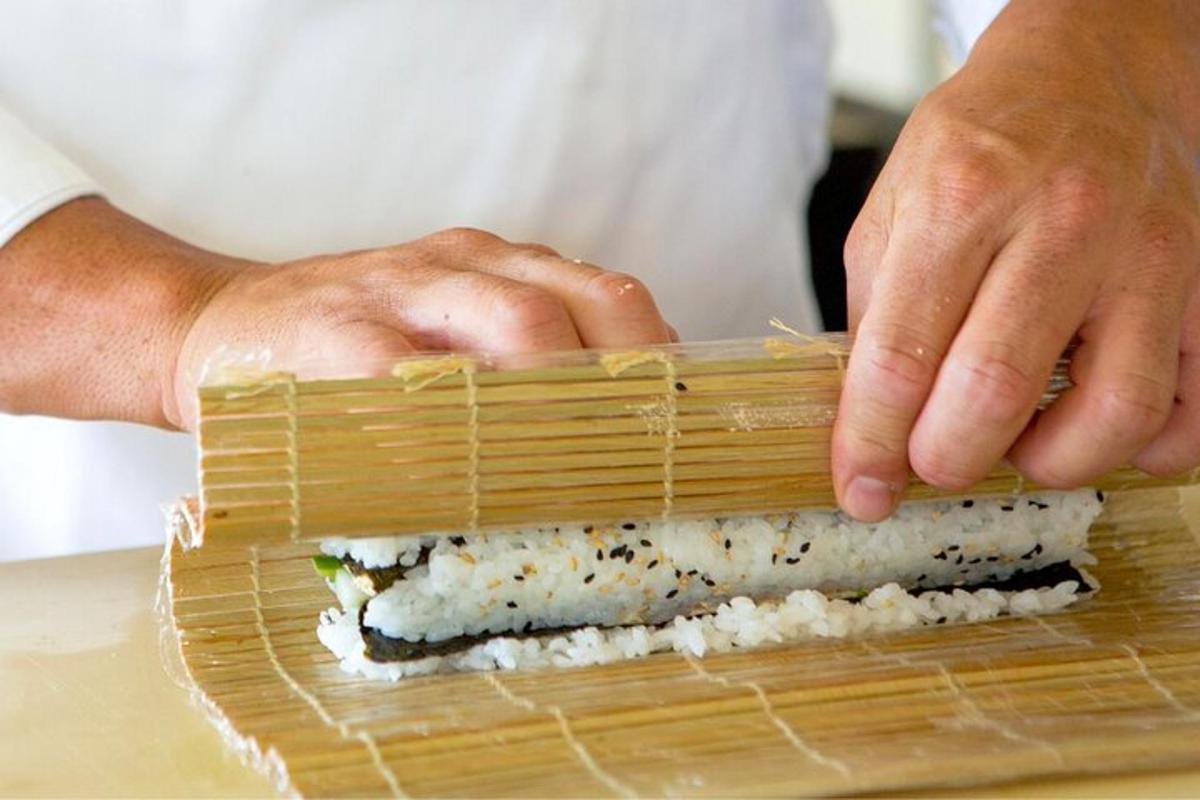 seorang tukang masak sedang membuat sushi dalam bakul buluh