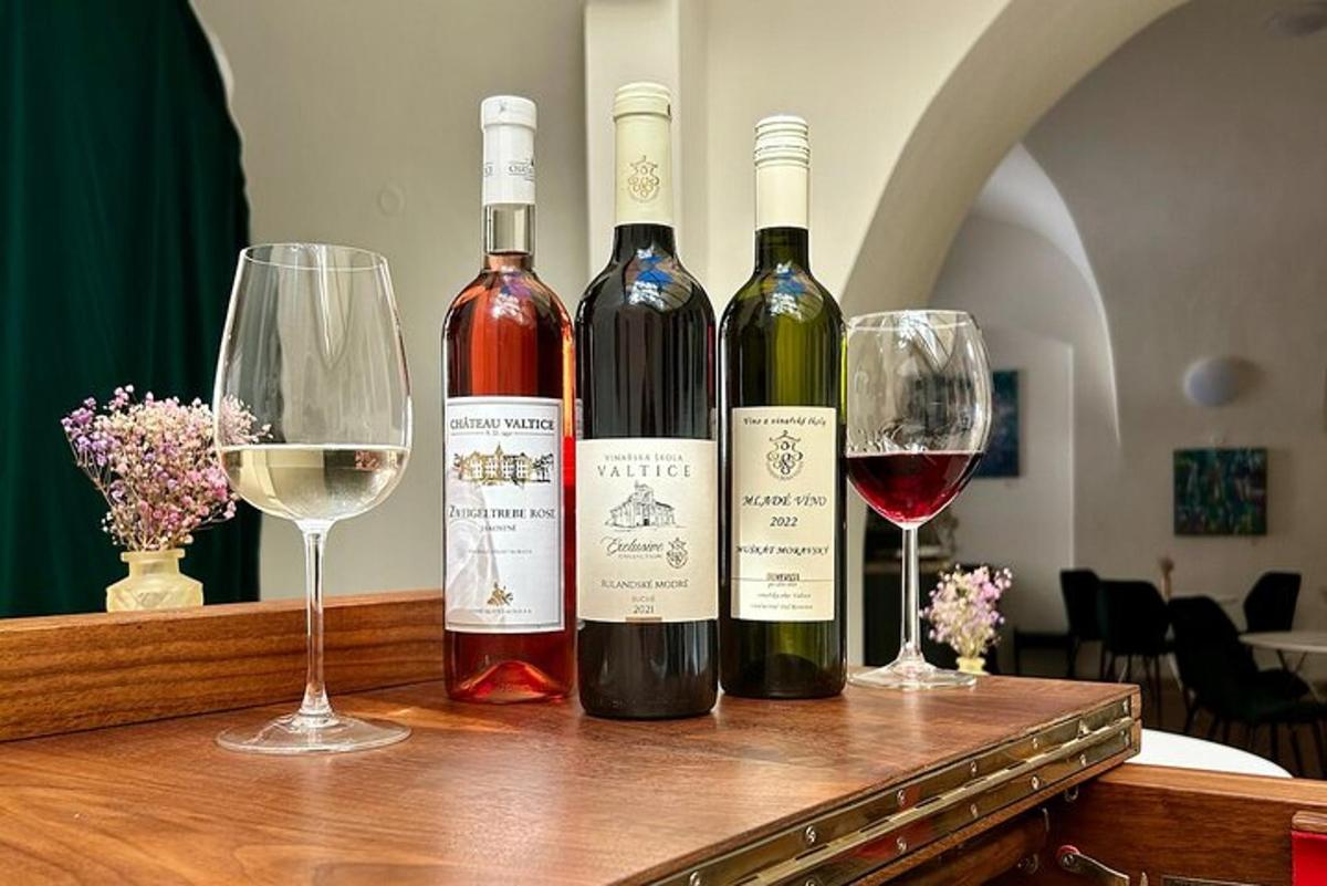 três garrafas de vinho sobre uma mesa com taças de vinho
