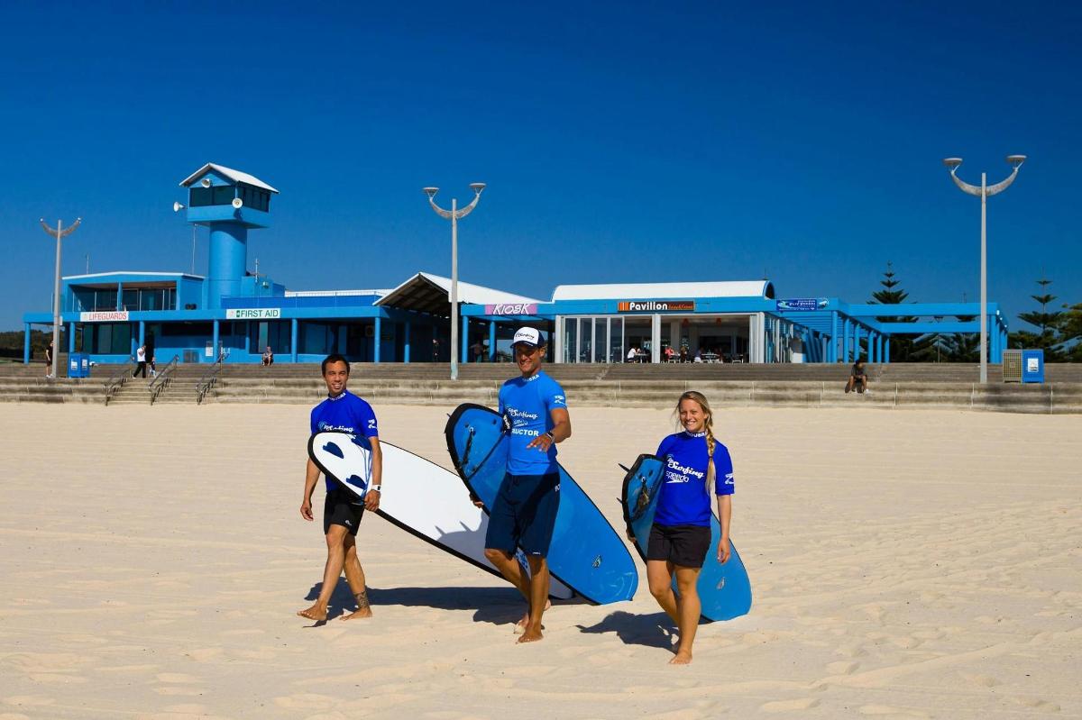 un grup de persones dempeus a la platja amb taules de surf
