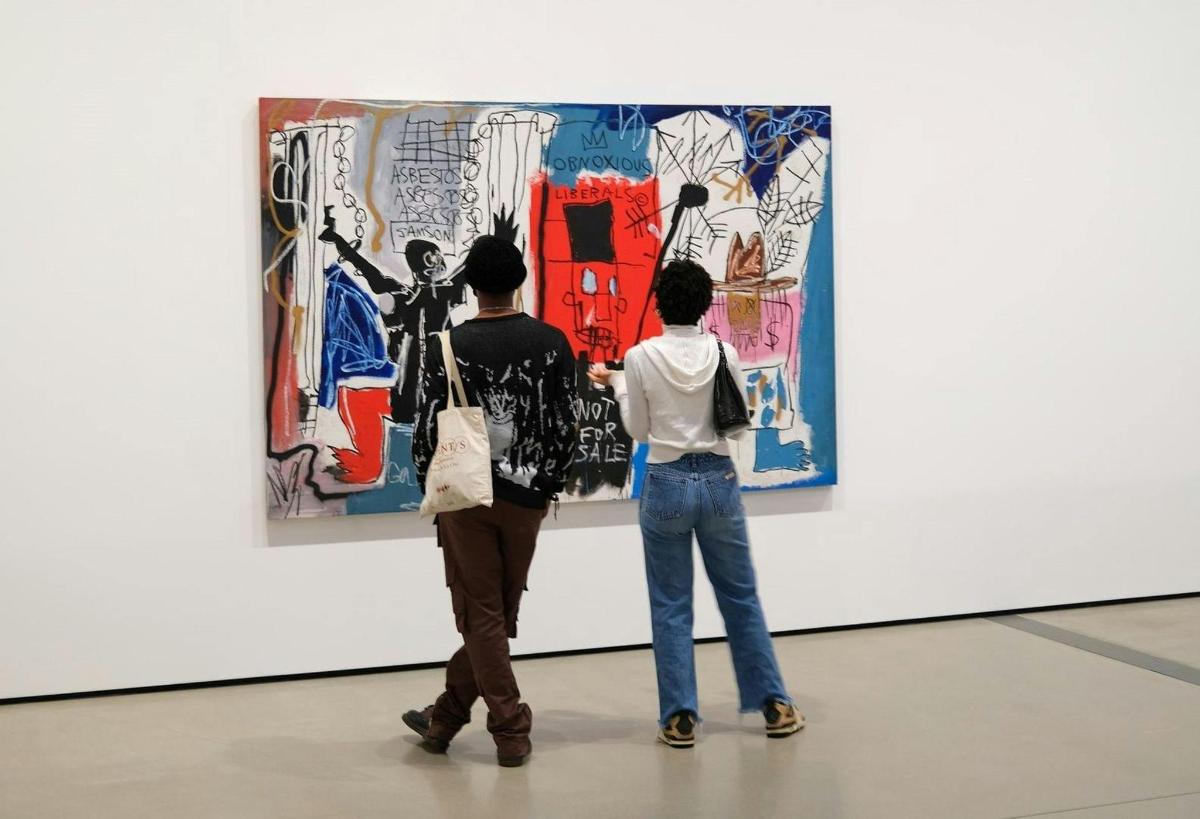 duas pessoas olhando para uma pintura em uma exposição de arte