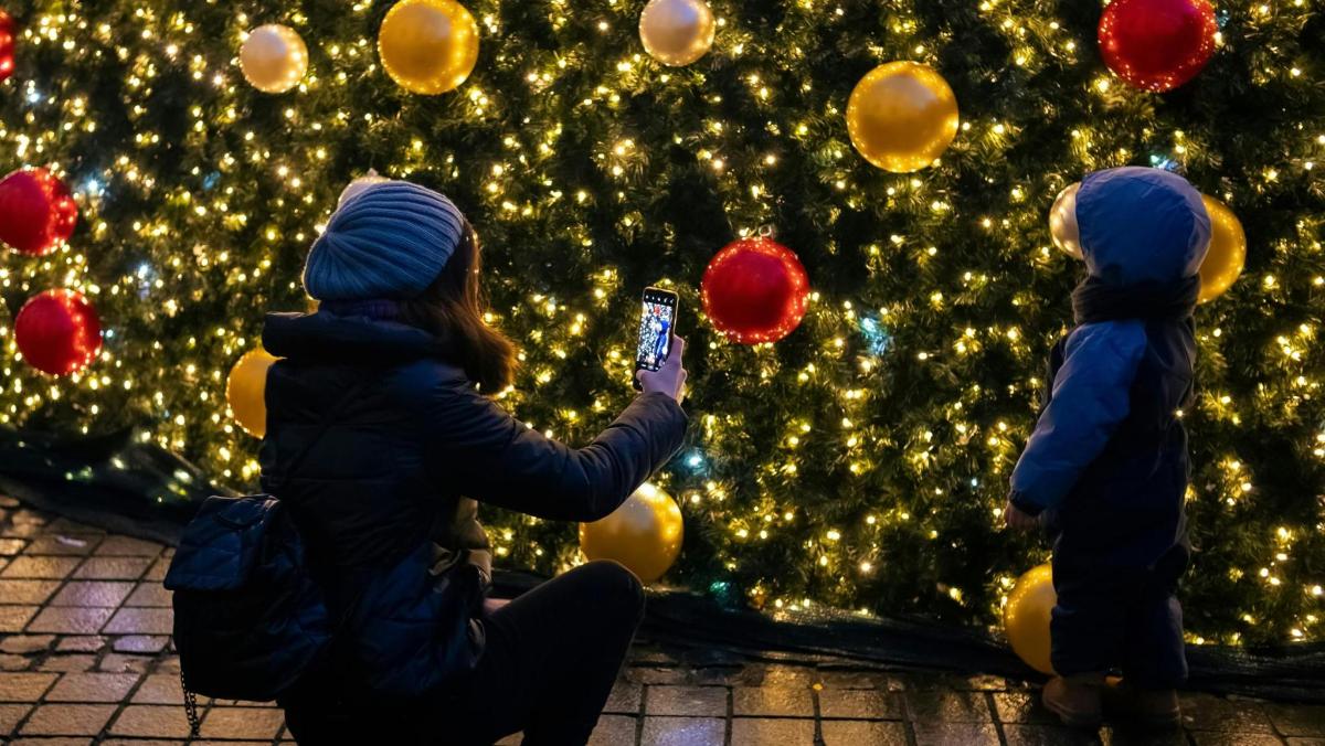 Dos niños tomando fotografías de un árbol de Navidad