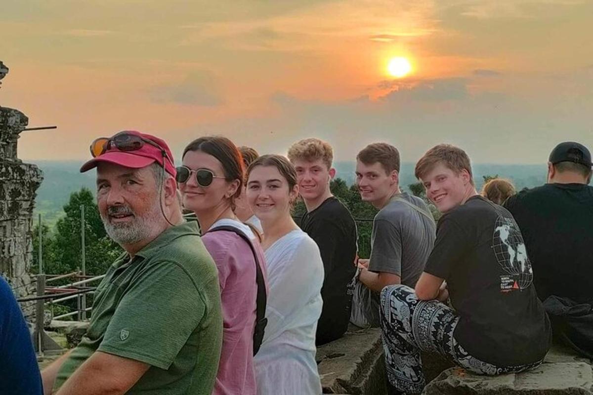 un gruppo di persone sedute su un muro al tramonto