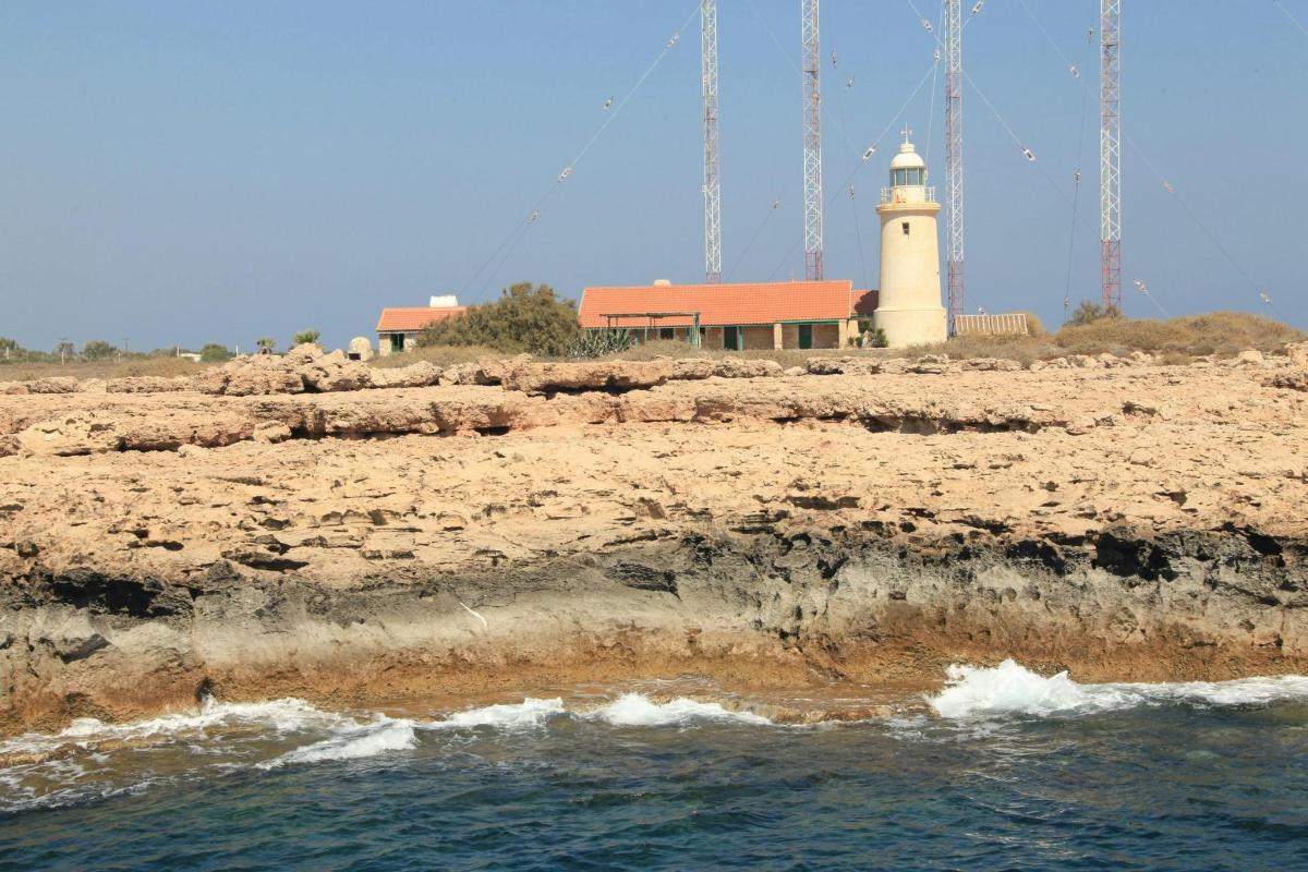 Un faro situado encima de una playa junto al agua.