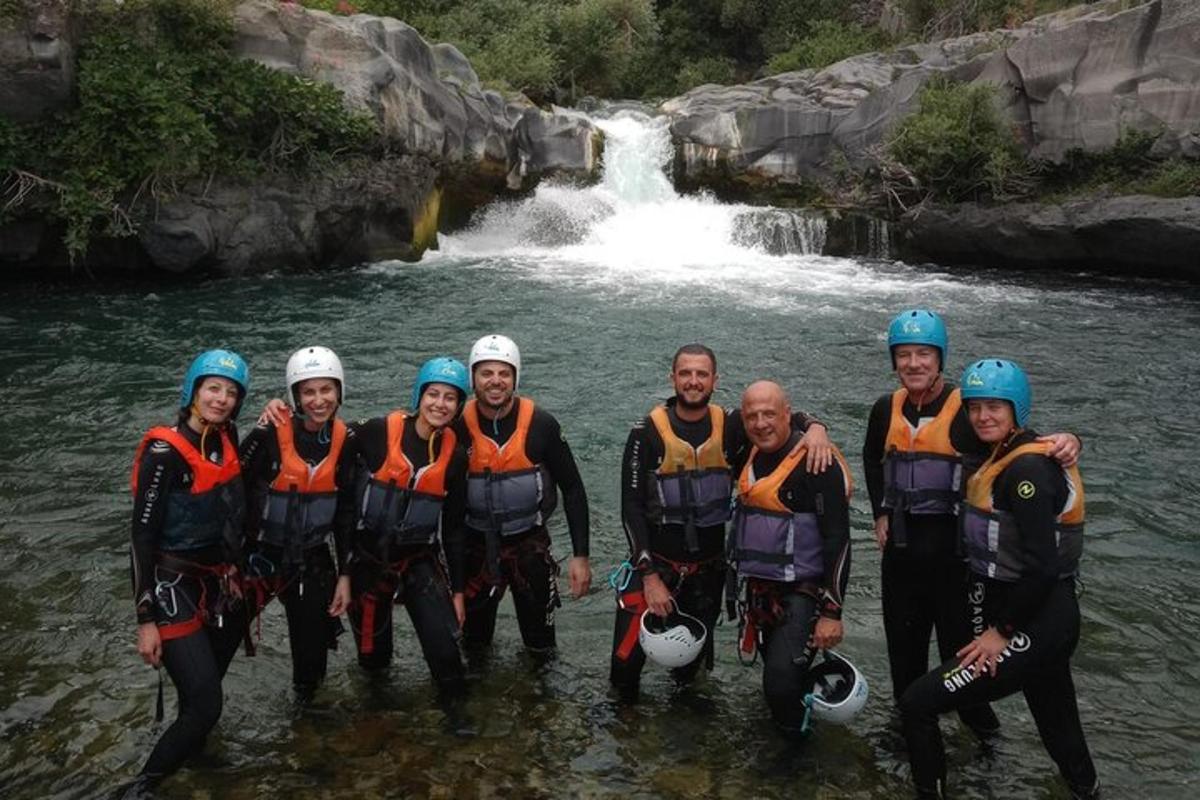 група људи стоји у води испред водопада