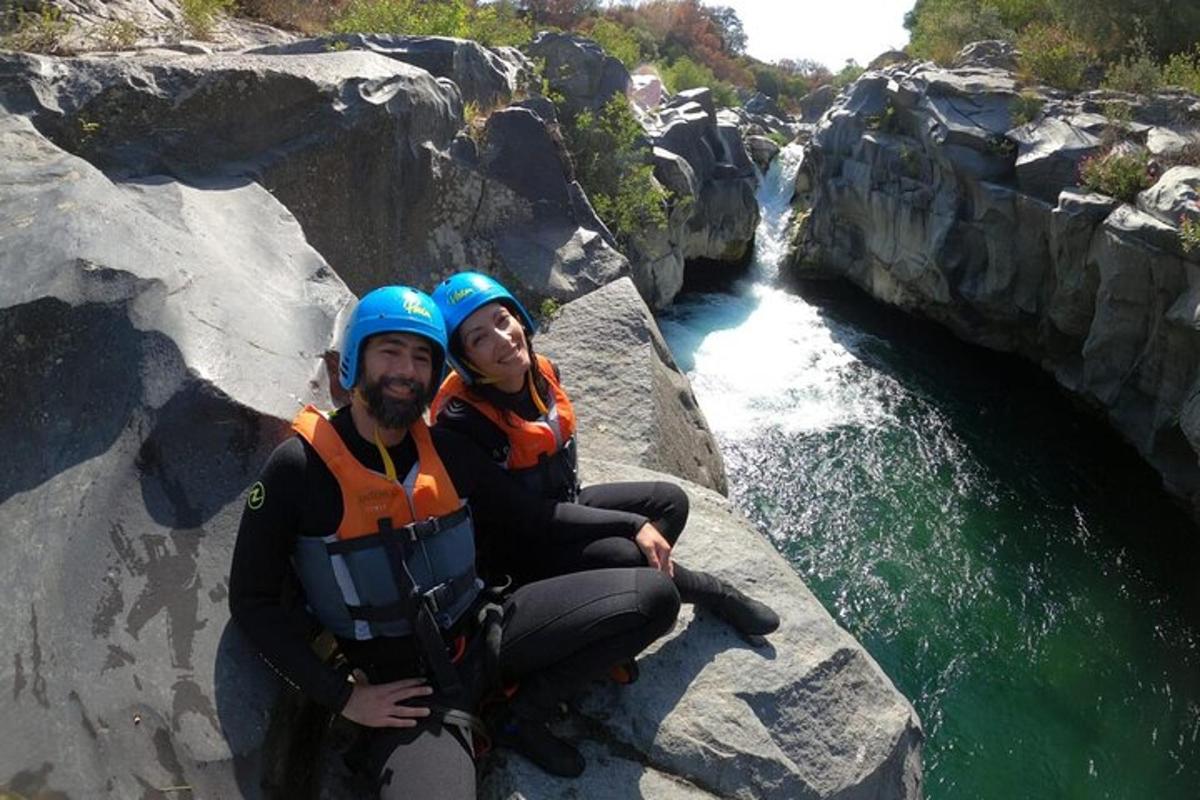 un uomo e una donna seduti su una roccia vicino a un fiume