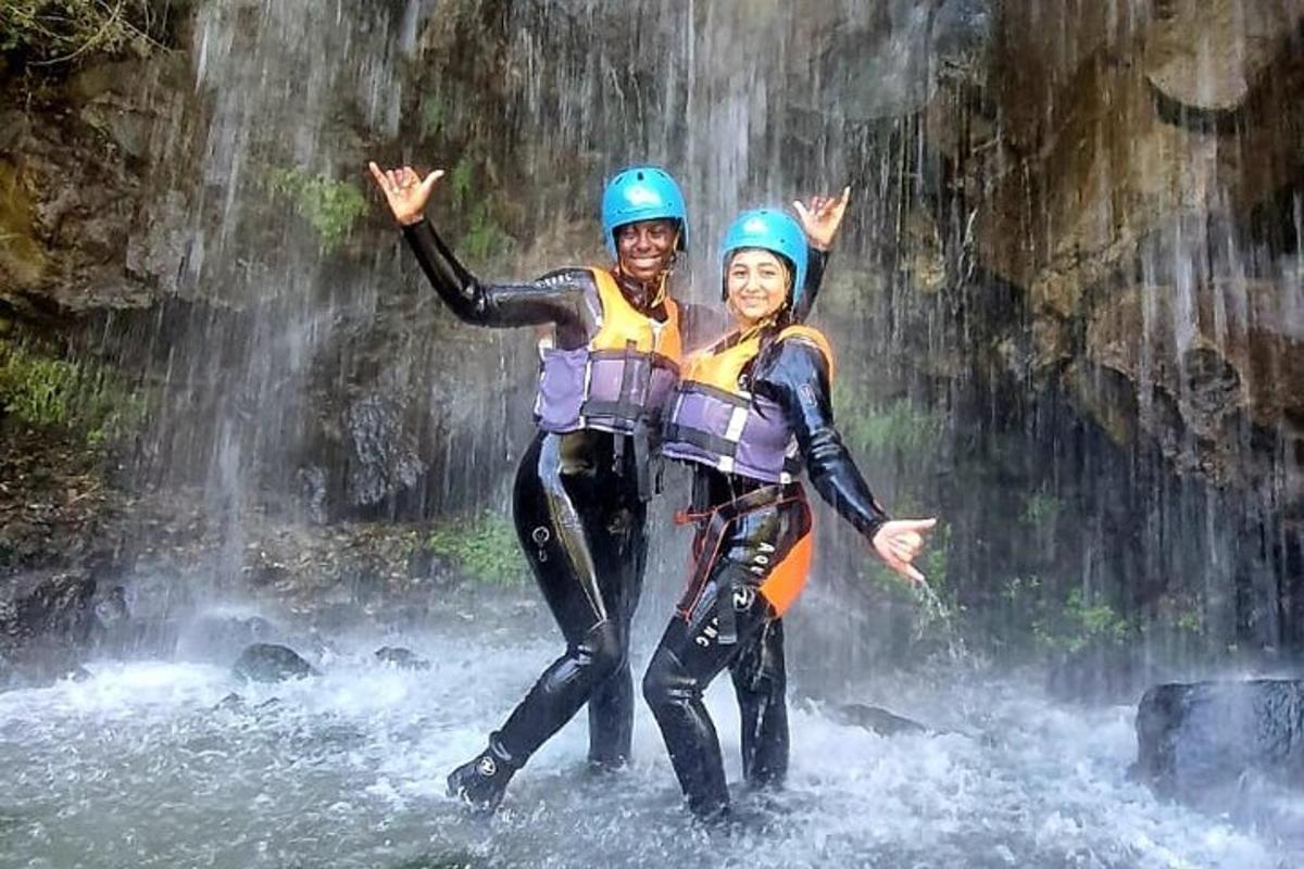 due persone in piedi nell'acqua di fronte a una cascata
