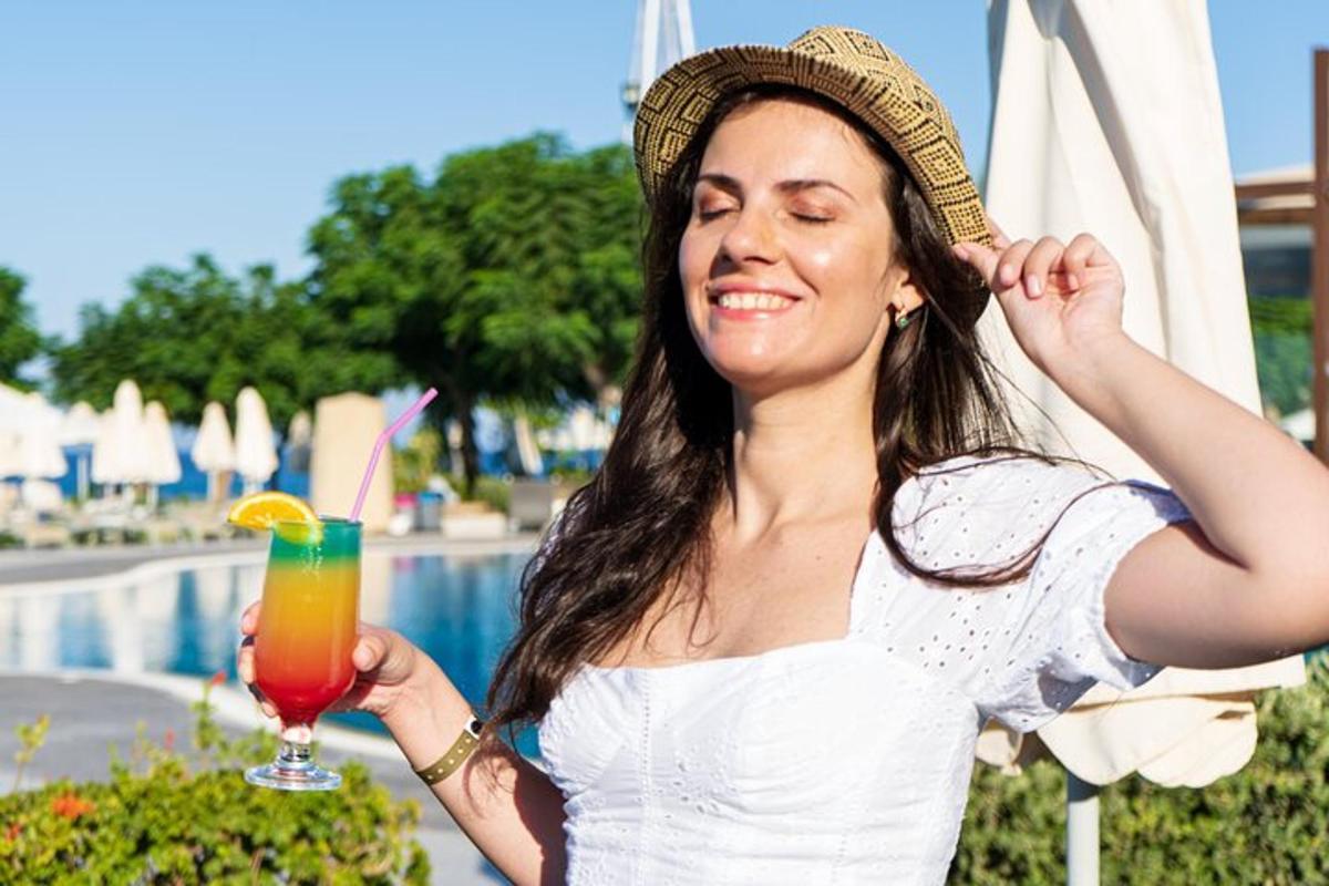 uma mulher segurando uma bebida ao lado de uma piscina