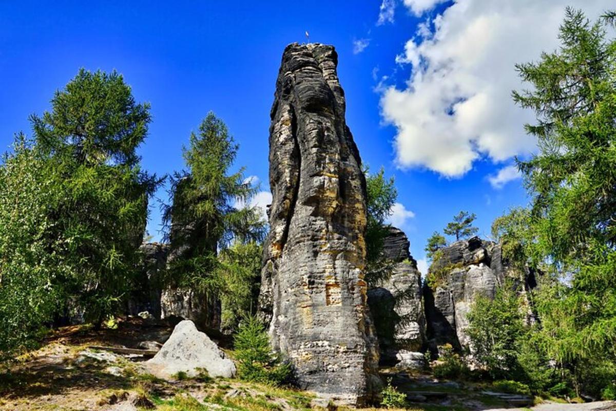 ένας ψηλός σχηματισμός βράχων μπροστά από μερικά δέντρα