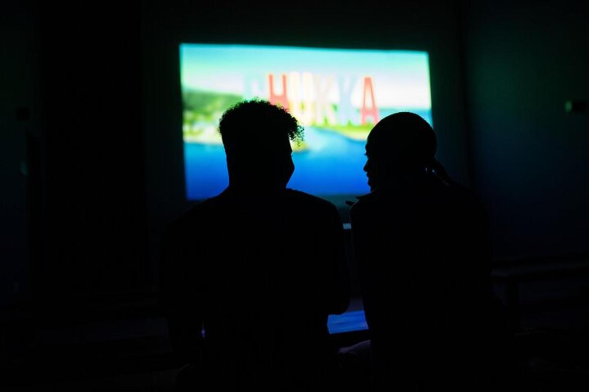 dva lidé stojící před televizí v temné místnosti