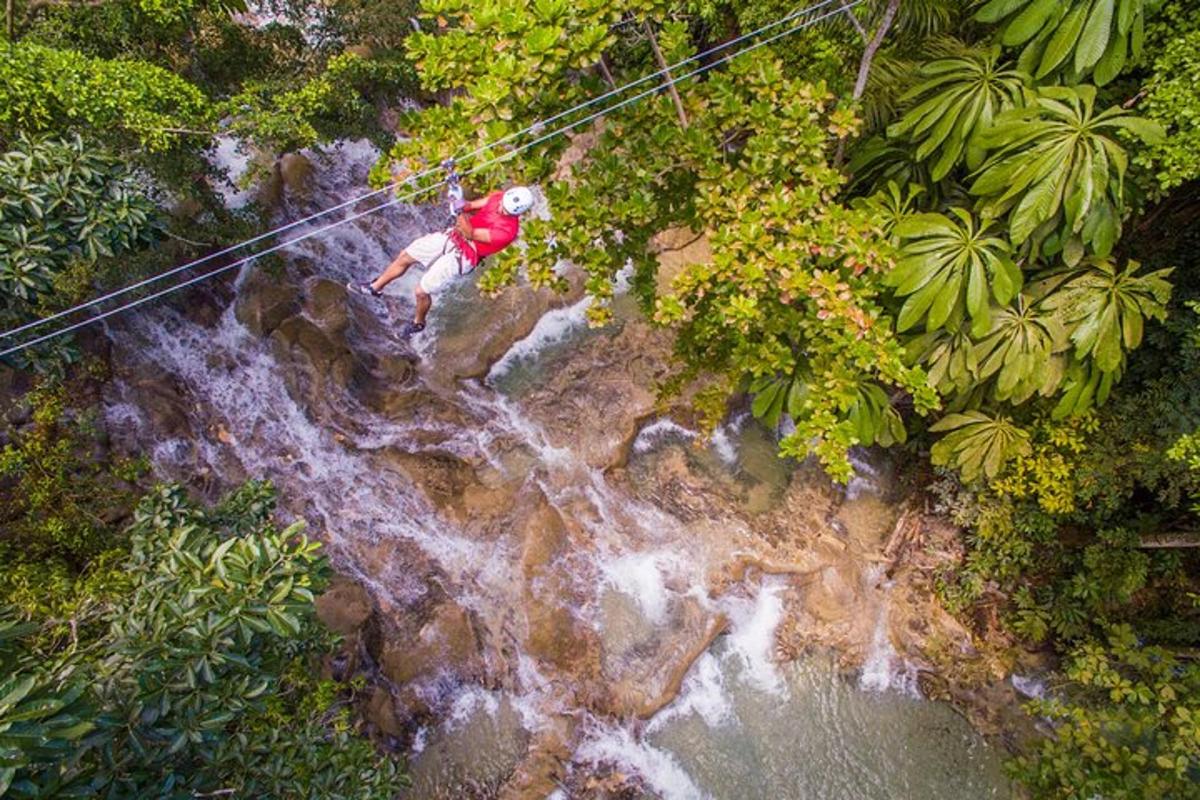 un home pujant en tirolina sobre una cascada