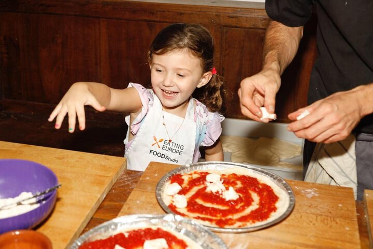 una bambina seduta a un tavolo che prepara una pizza