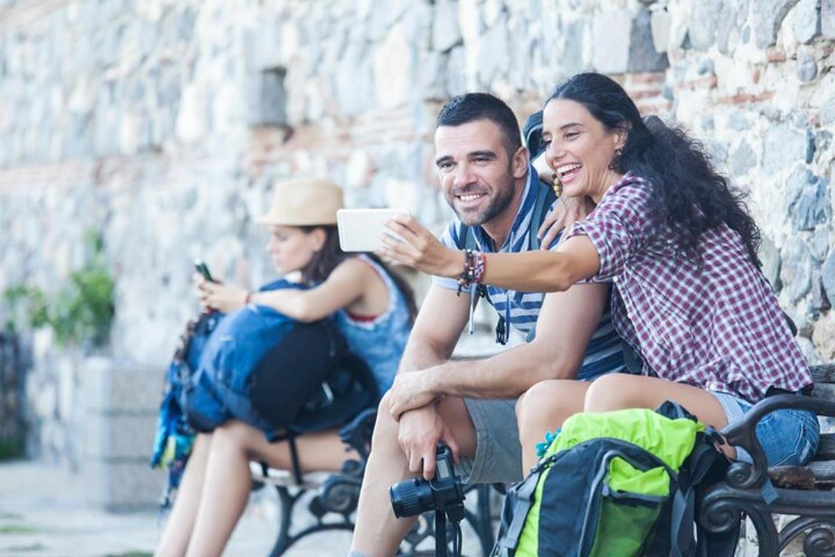 skupina lidí sedících na lavičce a dívajících se do mobilního telefonu