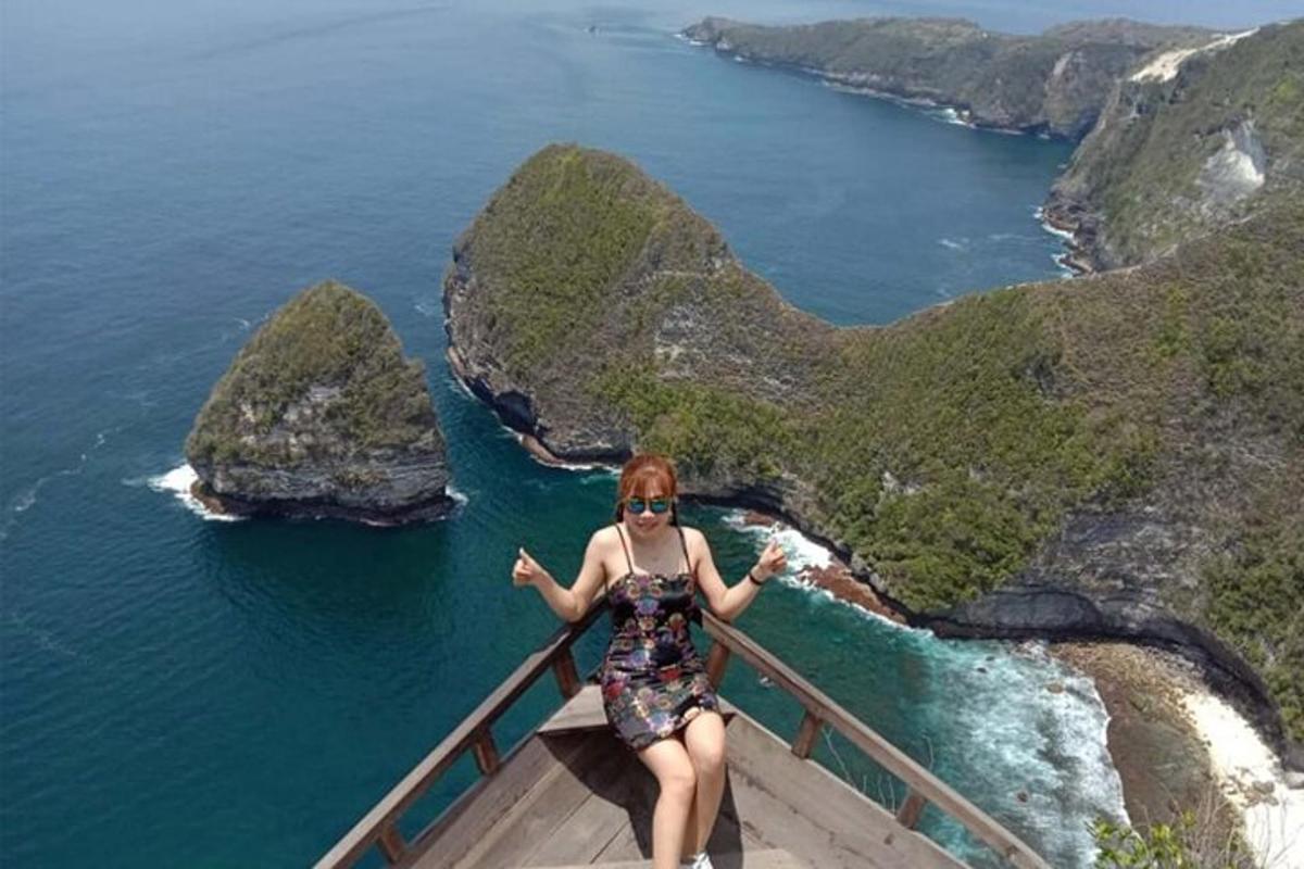 žena sedící na mostě s výhledem na oceán