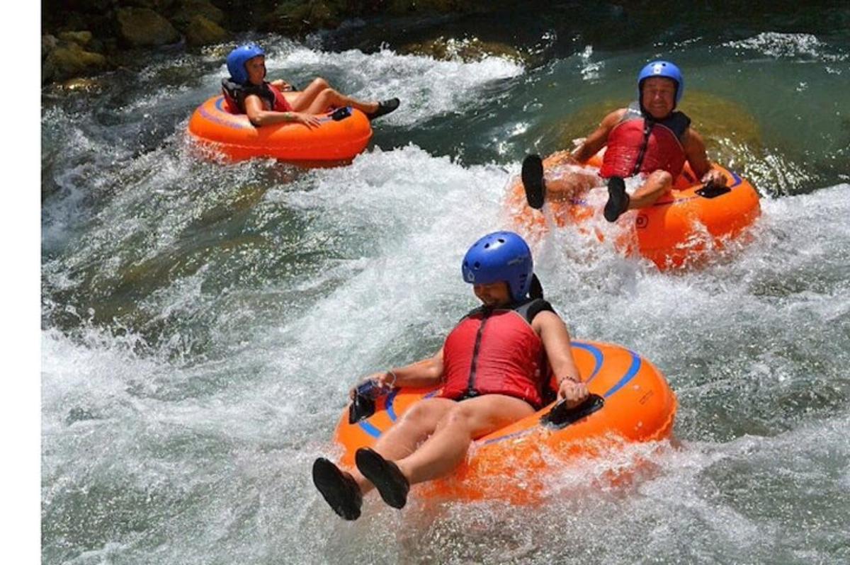 tre persone che scendono in rafting lungo un fiume su gommoni arancioni