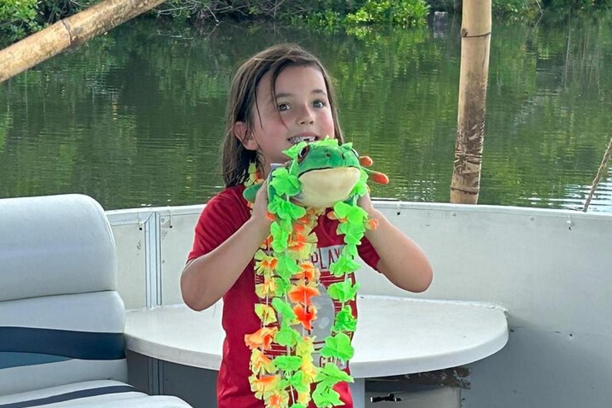 a little girl holding a stuffed dinosaur on a boat