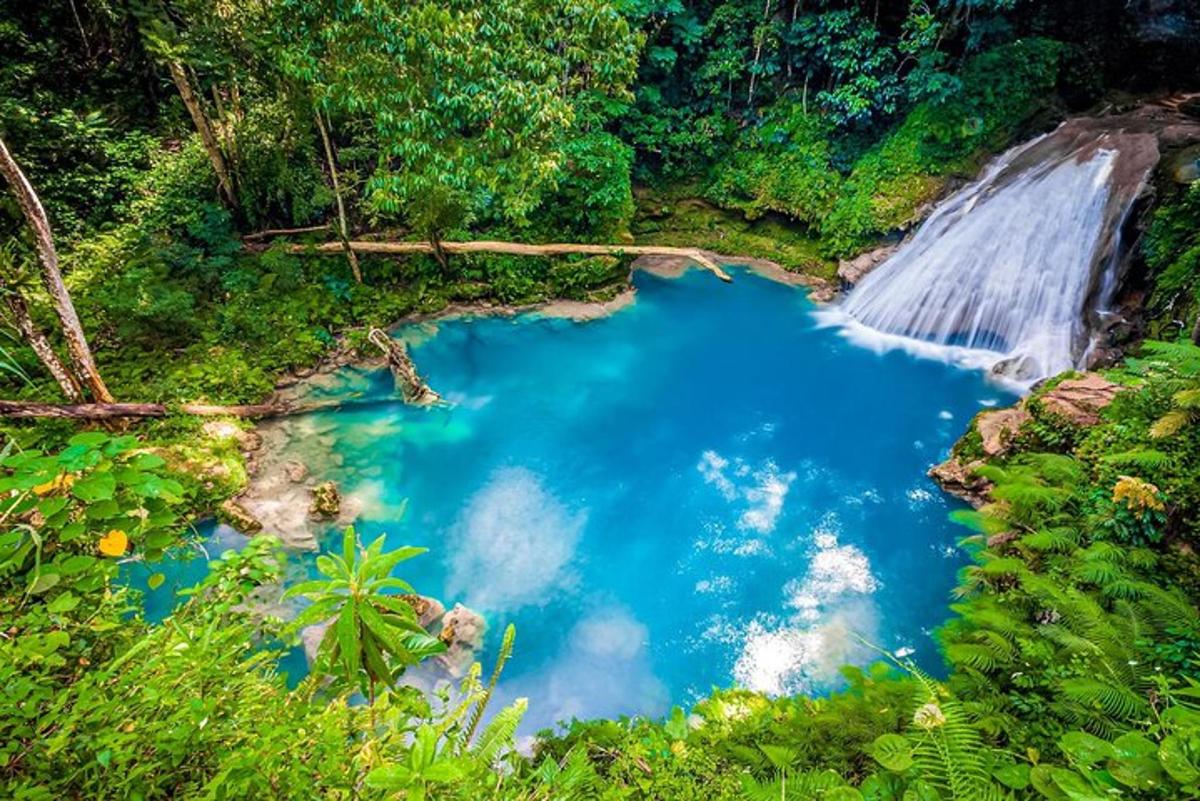 a blue pool of water in front of a waterfall