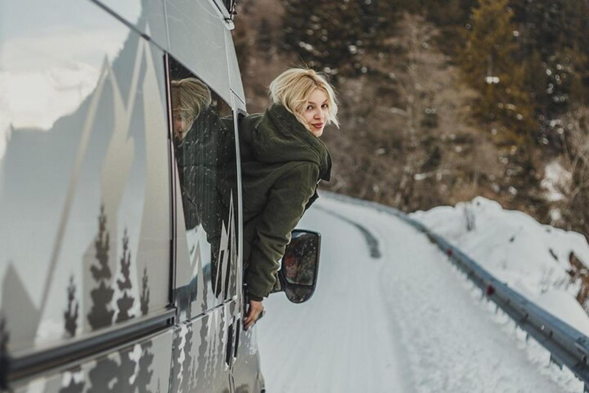 a woman looking out the window of a vehicle in the snow