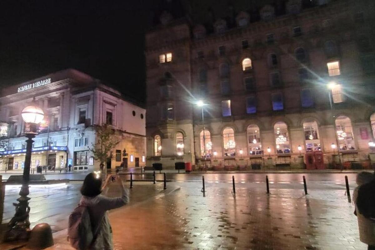 osoba, ktorá v noci fotografuje budovu