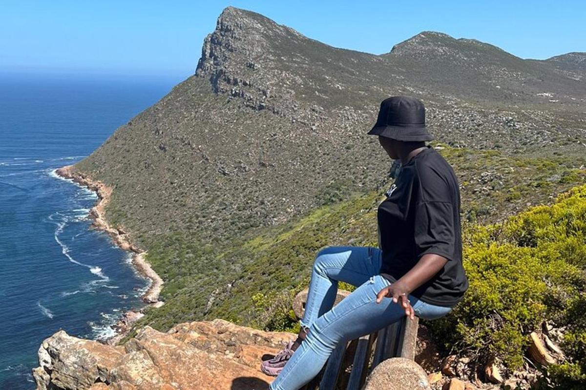um homem sentado em uma saliência olhando para o oceano