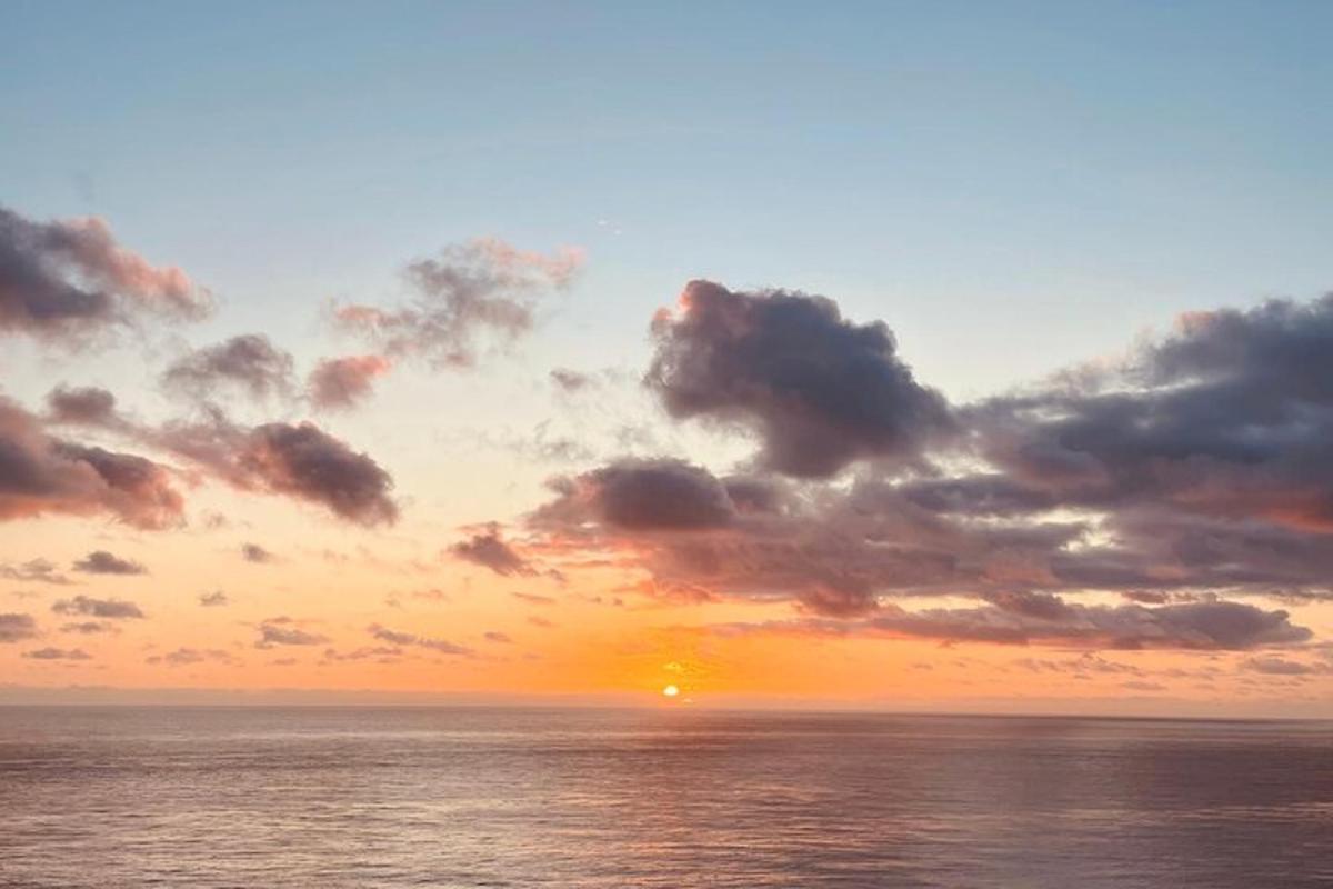 Západ slunce nad oceánem se zataženou oblohou