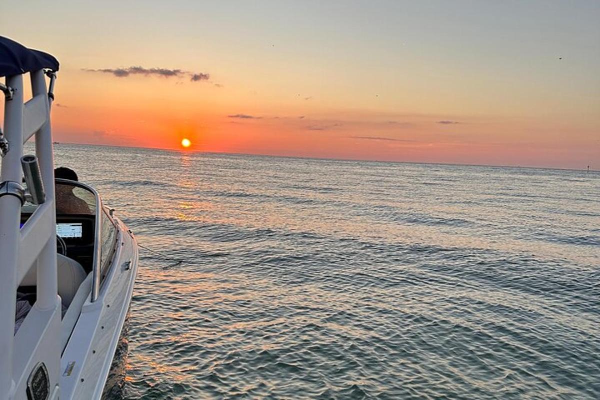 ein Boot im Meer mit dem Sonnenuntergang im Hintergrund