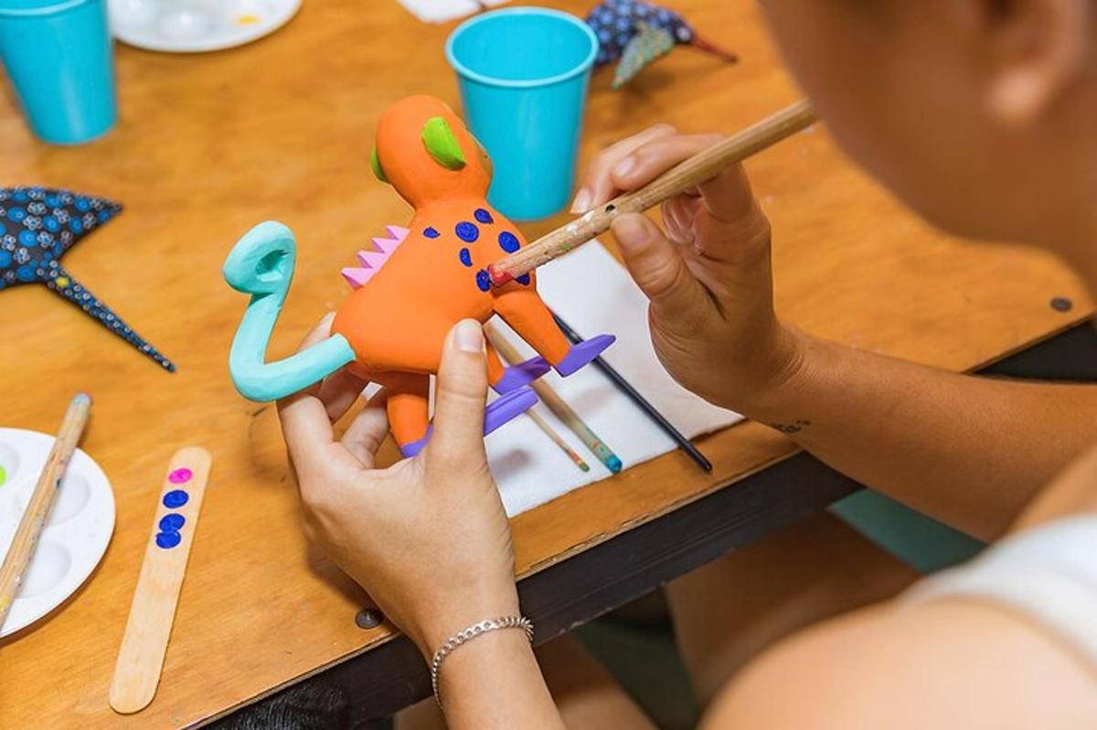 Una mujer pintando un juguete en una mesa de madera.