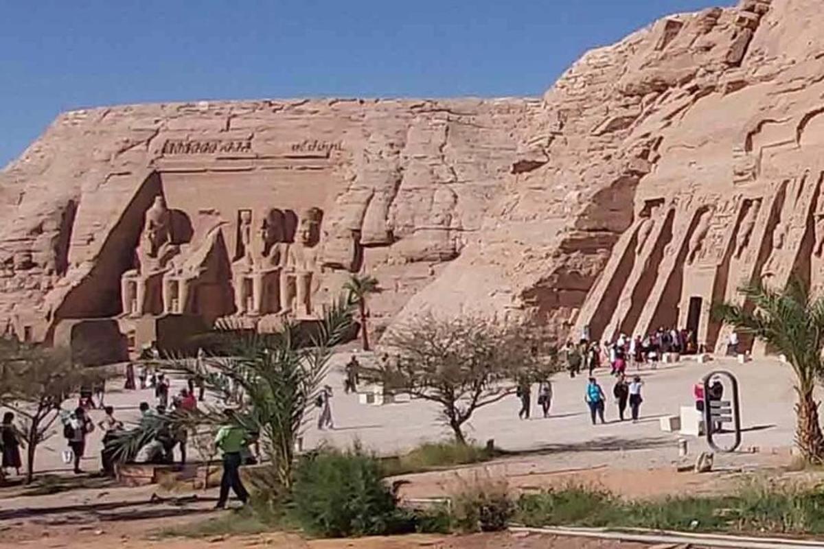 Un grupo de personas caminando frente a un acantilado de roca.