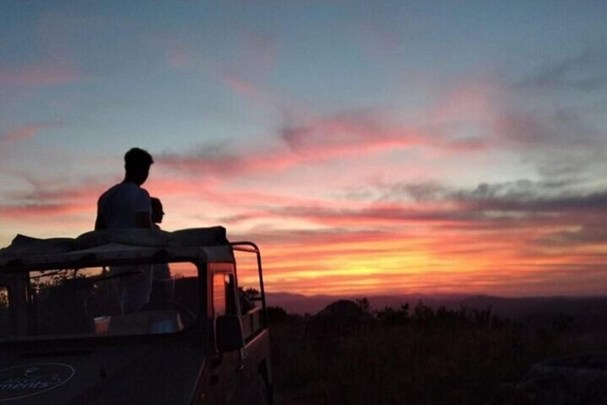 um homem sentado na traseira de um caminhão observando o pôr do sol