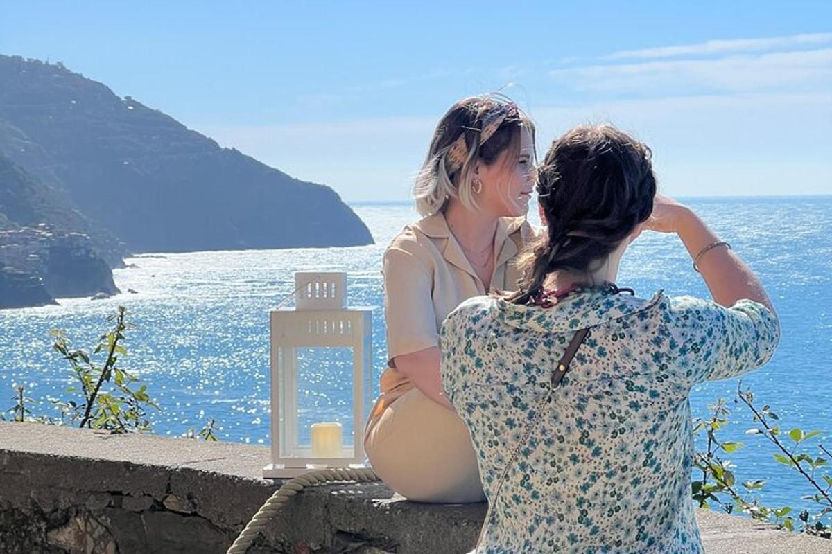 dve ženski, ki sedita na steni in gledata v ocean