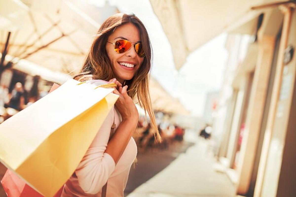 una donna con occhiali da sole che tiene in mano una borsa della spesa
