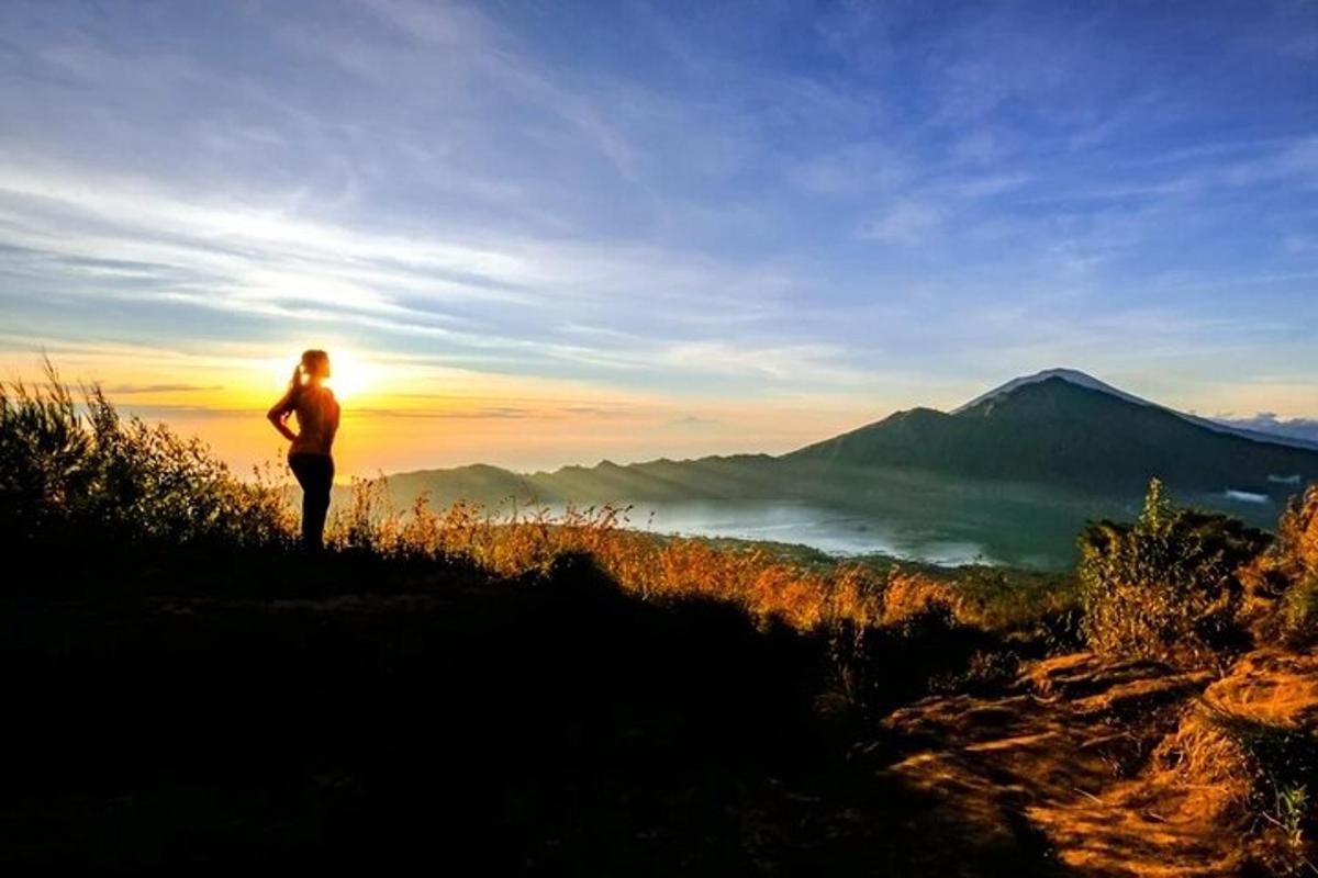 một người đứng trên đỉnh đồi có núi