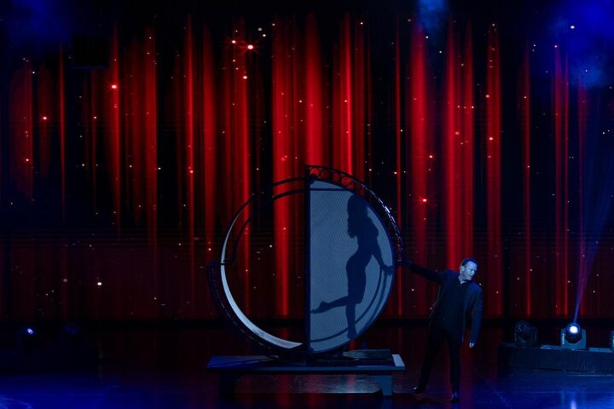 a man standing on a stage in front of a mirror